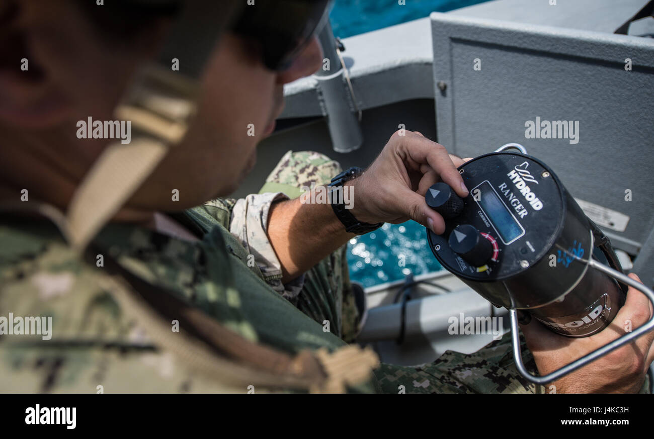 Un marin affecté à l'unité mobile de destruction des engins explosifs (5) 142 EODMU5 peloton utilise un dispositif de signalisation acoustique à bord d'une rivière côtière 1 Groupe Guam Détachement MK VI le bateau de patrouille pour recevoir les mises à jour de statut d'un véhicule sous-marin sans pilote au large de Saipan 9 mai 2017. EODMU5 est actuellement en train de tester sa capacité à déployer des actifs de différentes plates-formes, y compris des hélicoptères et des bateaux de patrouille, d'augmenter son interopérabilité adaptative. EODMU5 mène la lutte contre les mines, engins explosifs improvisés, les opérations de sécurité rend les dangers d'explosion et désarme explosifs sous-marins tels que Banque D'Images