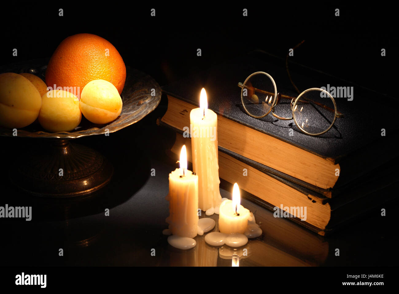 Vintage still life with fruits et de vieux livres près de bougies d'éclairage Banque D'Images