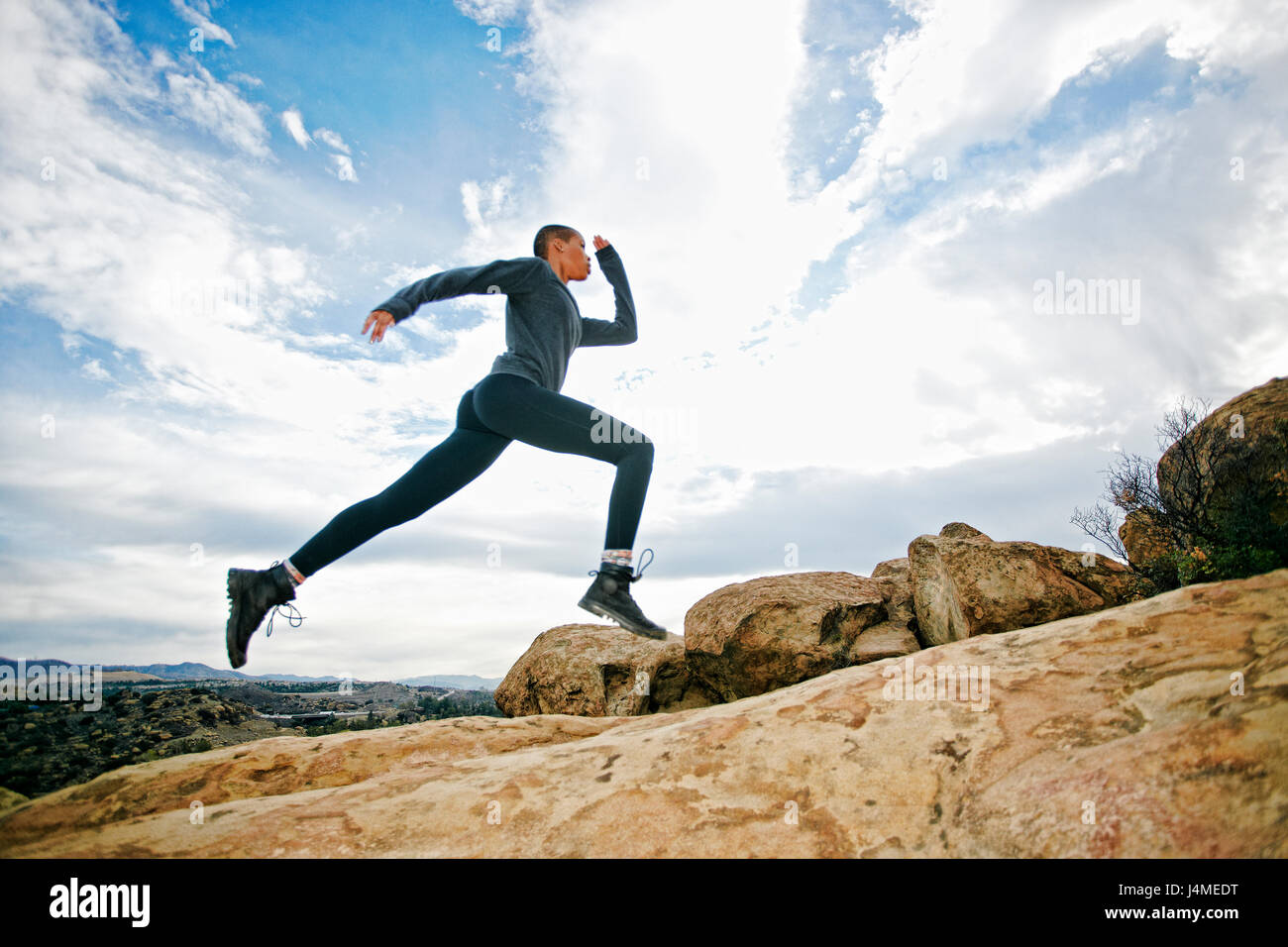 Black woman running on rock formation Banque D'Images