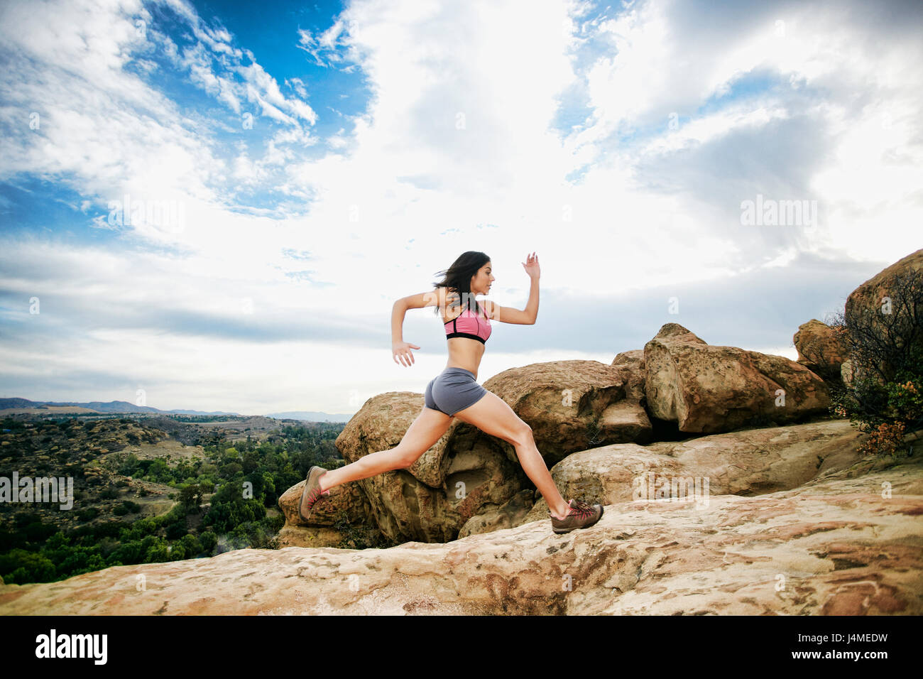 Hispanic woman running on rock formation Banque D'Images