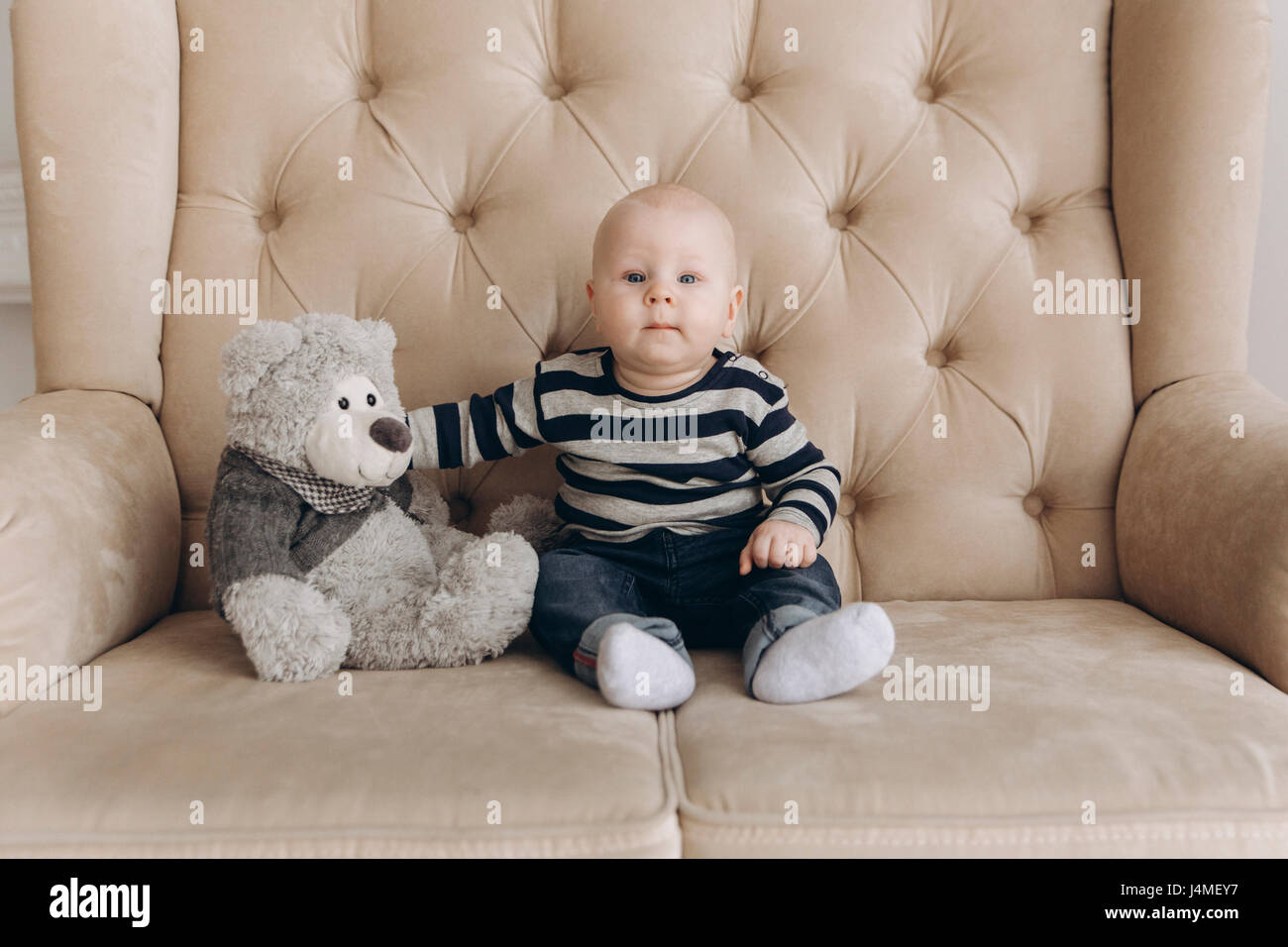 Portrait of Caucasian baby boy sitting on love siège avec ours Banque D'Images