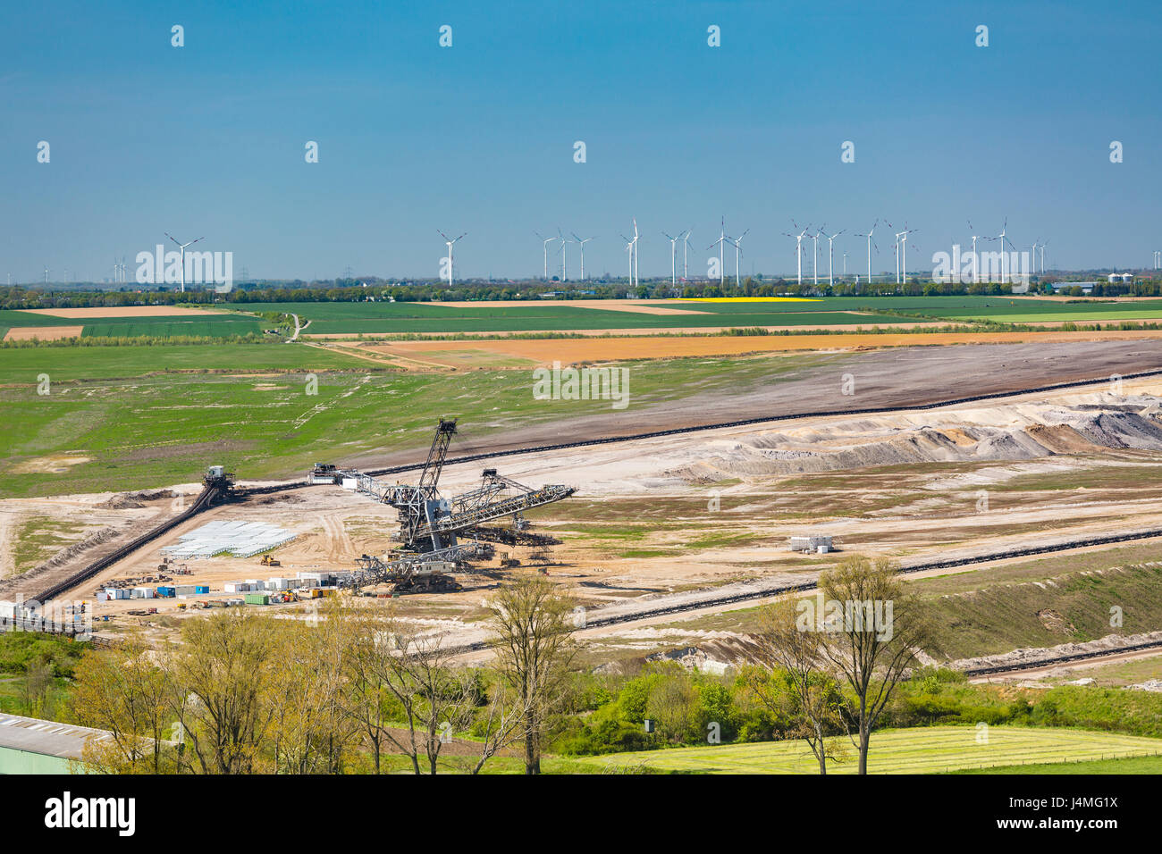 Une mine à ciel ouvert de lignite en face d'un grand parc d'éoliennes représentant la modification des combustibles fossiles aux énergies renouvelables Banque D'Images