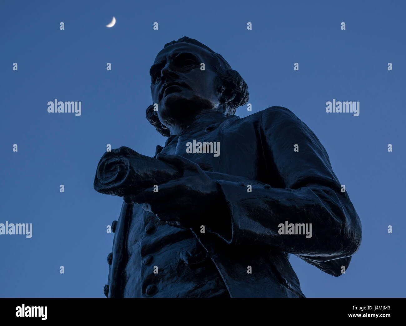 Un croissant de lune au-dessus de la statue du capitaine James Cook dans le port de Victoria, Colombie-Britannique, Canada. Banque D'Images