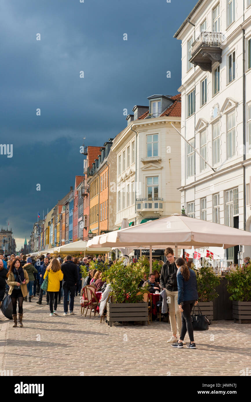 Sombres nuages sur l'occupé et coloré quayside de Nyhavn, dans le centre de Copenhague. Danemark. région touristique avec bars et restaurants. Banque D'Images