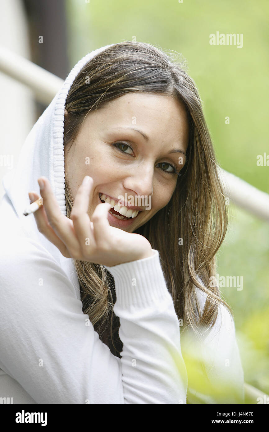 Sourire, femme, pull capuche, cigarette, fumée, portrait, Banque D'Images