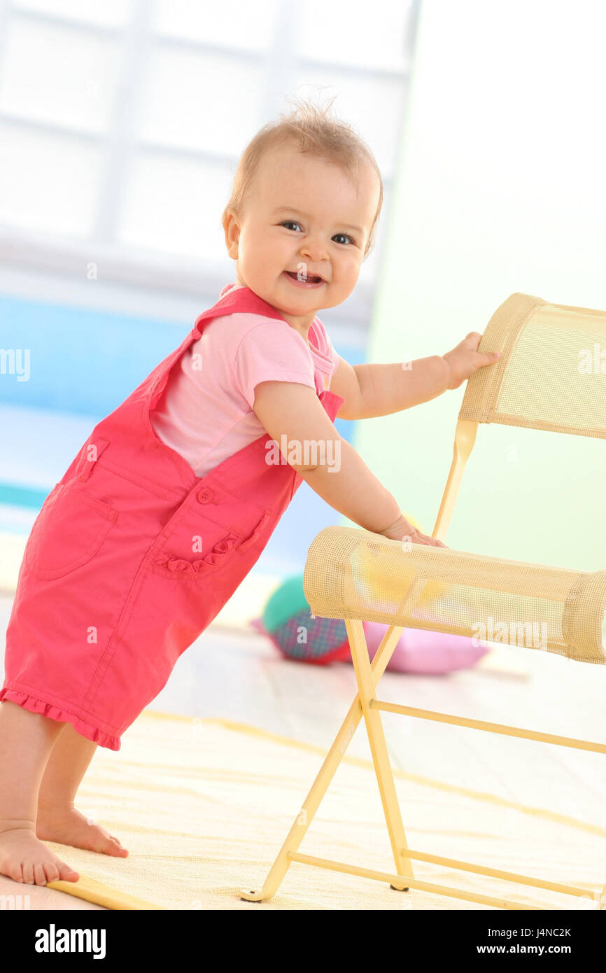 Bébé, 9 mois, sourire, tenir sur une chaise, debout, Banque D'Images