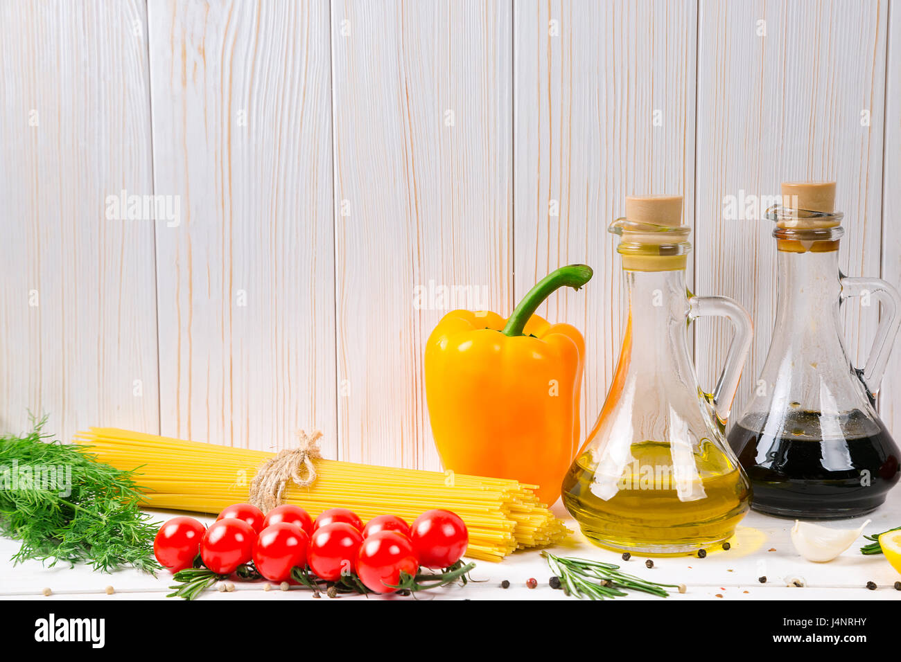 Spaghetti, tomates cerise, huile d'olive, d'herbes et épices sur fond de bois blanc. Définir pour des aliments sains. Ingrédients pour la salade. Banque D'Images