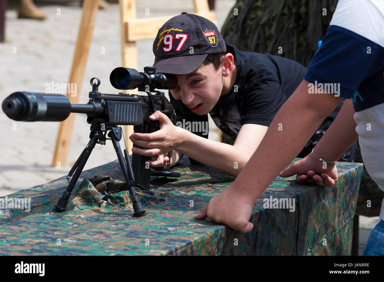 Un écolier tente un un fusil snipers pour célébrer le jour de l'indépendance géorgienne à Mtskheta dans la République de Géorgie. Banque D'Images