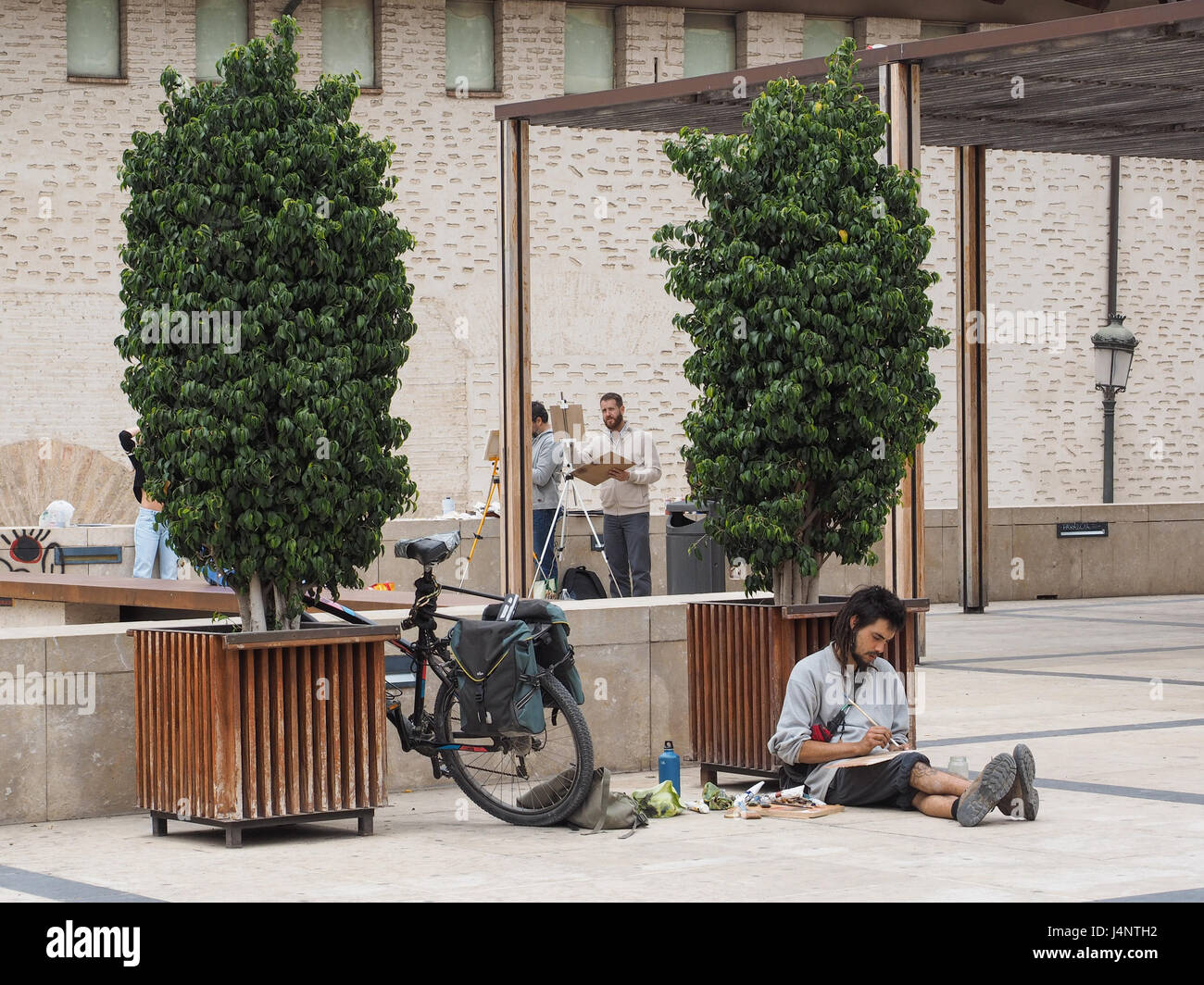 Artiste artistes travaillant dessin peinture dessin chevalets open air assis au sol plancher un permanent un chevalet location vélo soutenu femme assise Valencia Banque D'Images