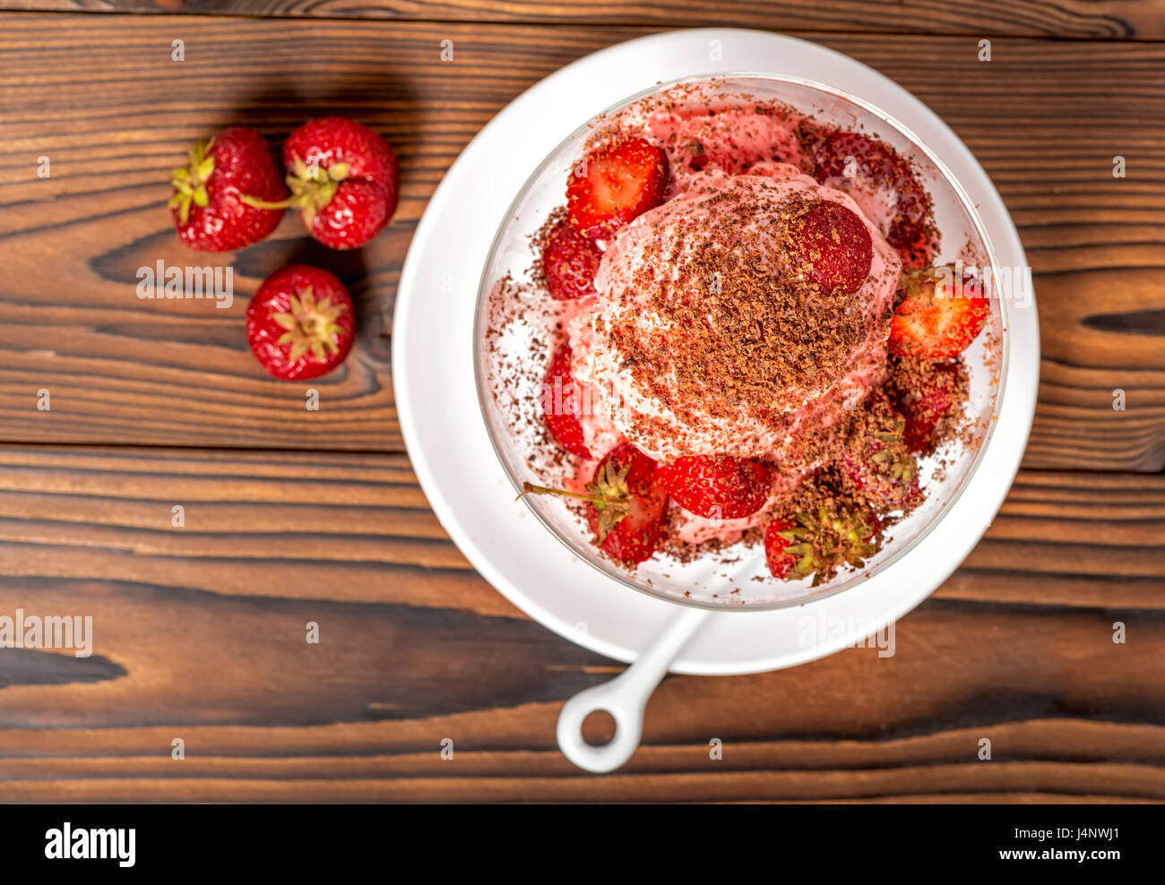 Vue de dessus de la fraise dessert vanille rose boules de glace avec du chocolat et des fraises fraîches saupoudrées sur table en bois Banque D'Images