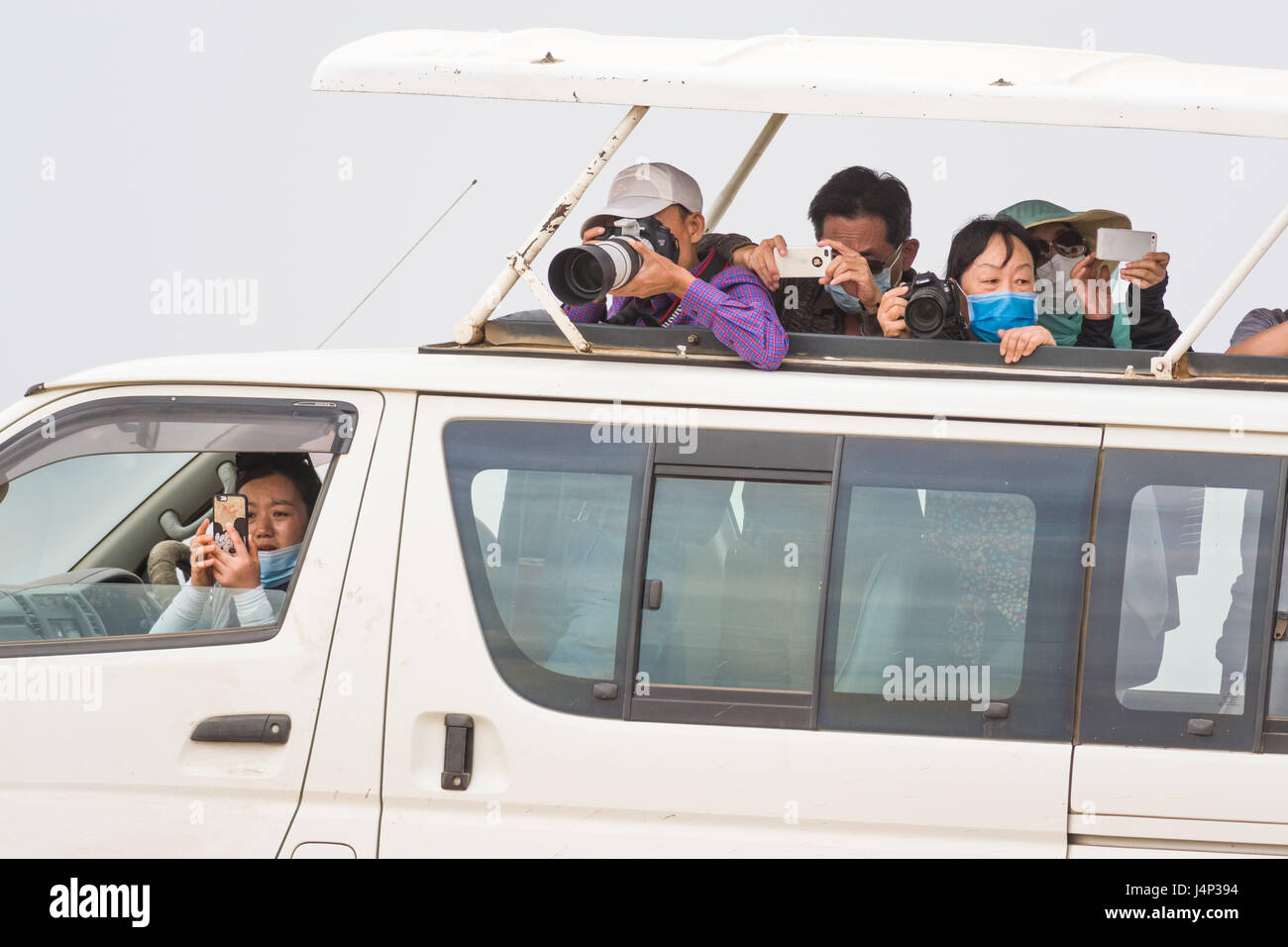 Les touristes asiatiques avec des caméras en toit ouvert Safari 4x4 véhicule, Maasai Mara, Kenya Banque D'Images