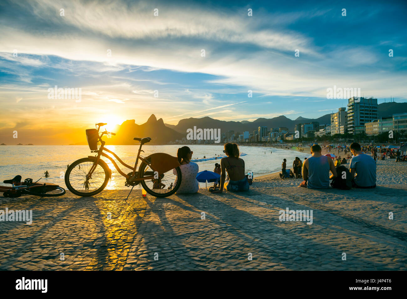 Les gens assis à regarder le coucher du soleil, l'Arpoador à une activité estivales les plus populaires pour les habitants et les touristes, à Rio de Janeiro, Brésil Banque D'Images