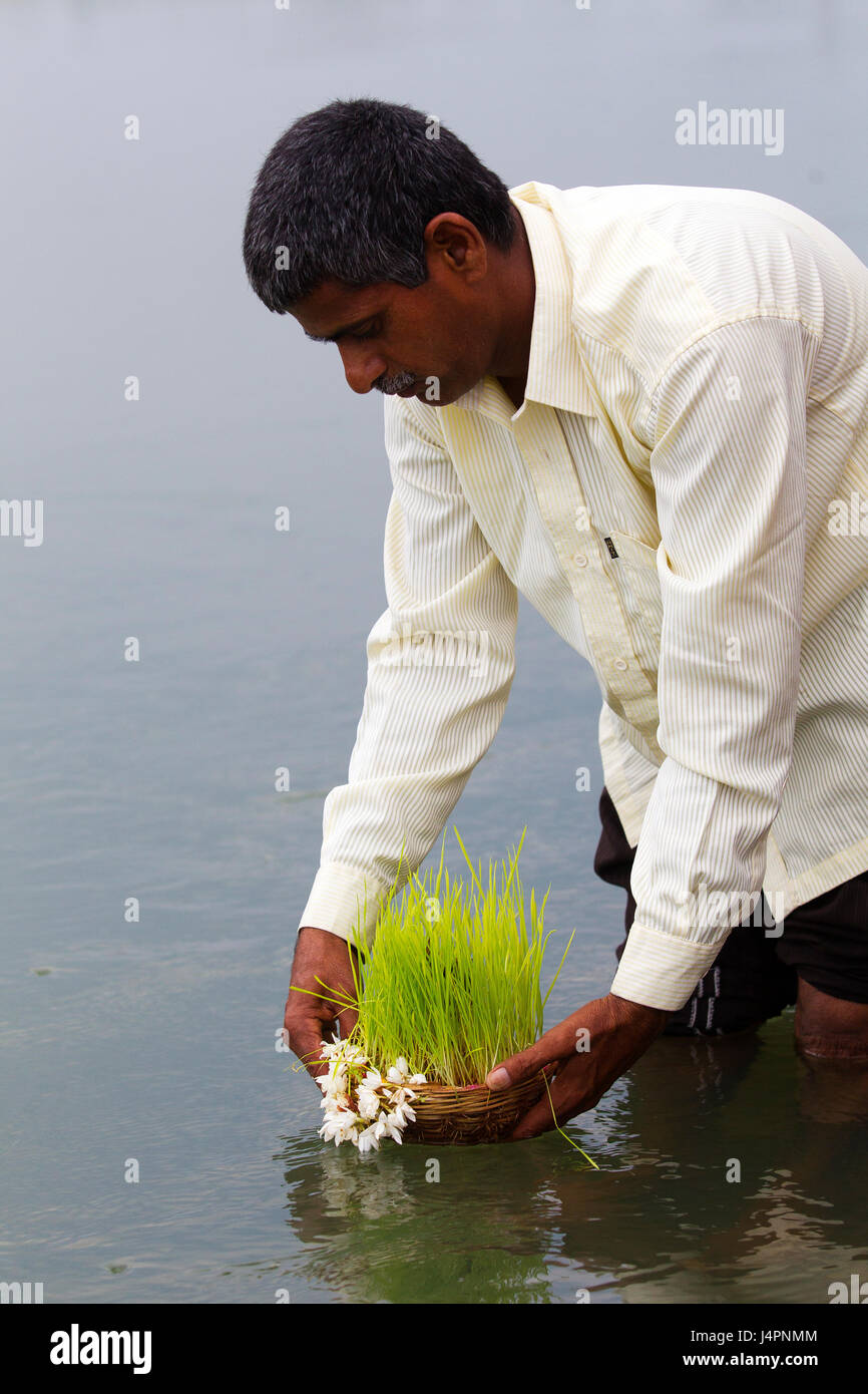 L'homme Indien avec une offrande à Dieu au Canal Tungabhadra, Hospet, Karnataka, Inde Banque D'Images