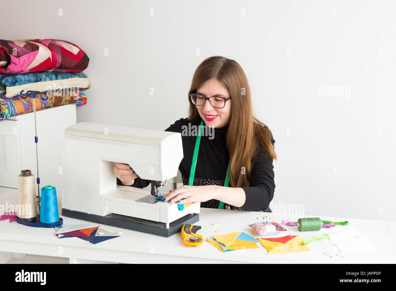 De couture et de quilt à l'atelier d'une jeune femme - sur mesure travaille dans un bureau avec une machine à coudre et de fils, tissus, aiguilles, épingles, boutons. Banque D'Images