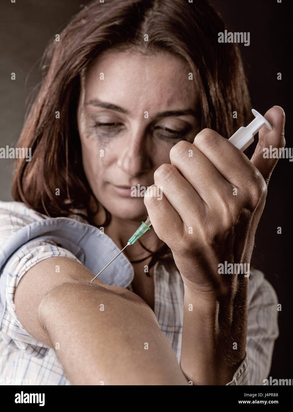 Jeune femme toxicomane avec seringue en action sur fond sombre Banque D'Images