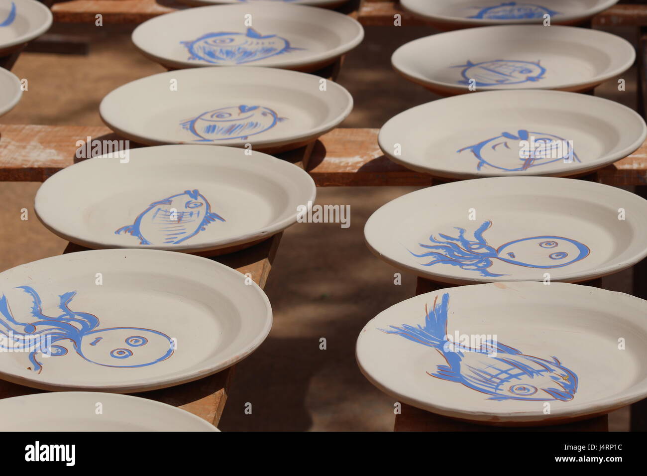 Les plaques de céramique espagnole avec des dessins de poissons bleus sur fond blanc sur des étagères de séchage au soleil Banque D'Images