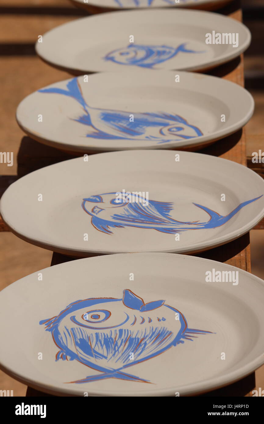 Les plaques de céramique espagnole avec des dessins de poissons bleus sur fond blanc sur des étagères de séchage au soleil Banque D'Images