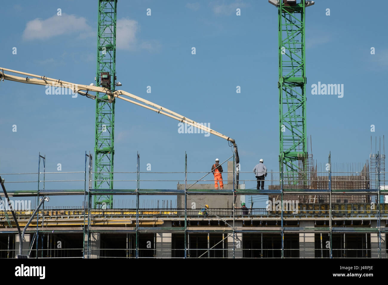 Les travailleurs de la construction sur des échafaudages le coulage de béton sur le chantier de construction du nouveau bâtiment Banque D'Images