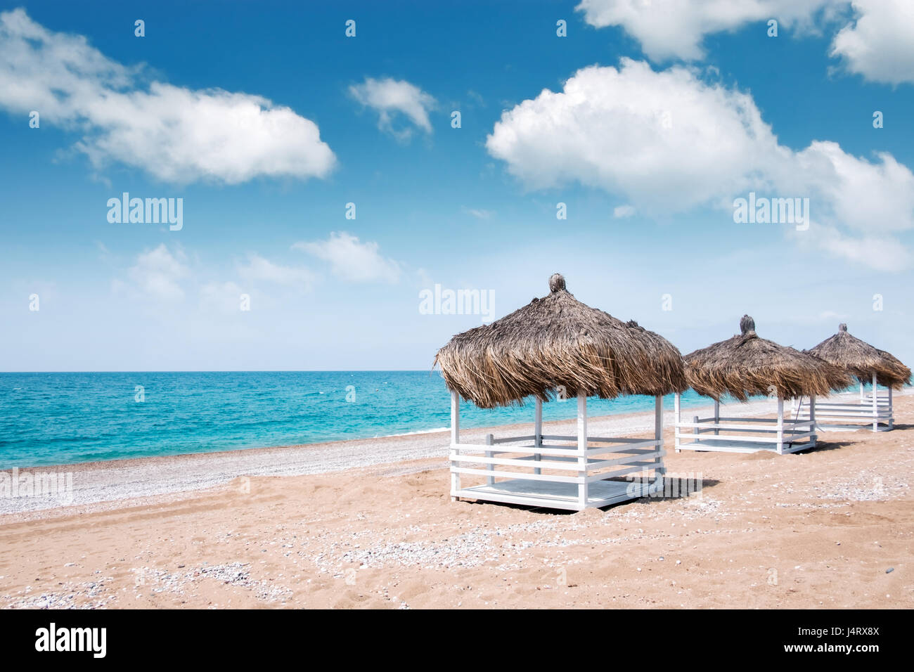 Tonnelles d'été sur la plage. Vue imprenable sur la mer méditerranée. Niches en bois blanc sur la journée ensoleillée. Ciel bleu et nuages moelleux Banque D'Images
