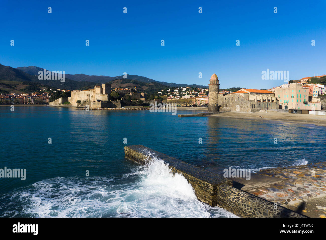 La ville de Collioure dans le Languedoc-Roussillon, dans le sud de la France est illustrée de la ville pier. Une onde est se briser contre le mur du port. La Cathédrale Banque D'Images