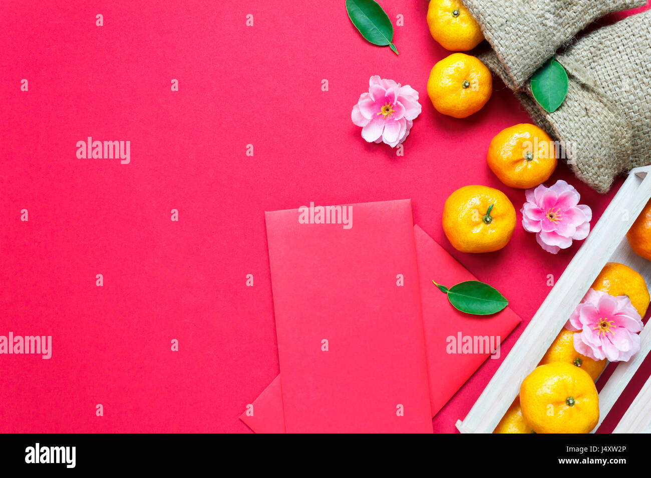 Haut afficher les accessoires le festival du Nouvel an chinois.décorations,orange,feuilles,panier Bois de prunier,paquet rouge sur fond rouge. Banque D'Images