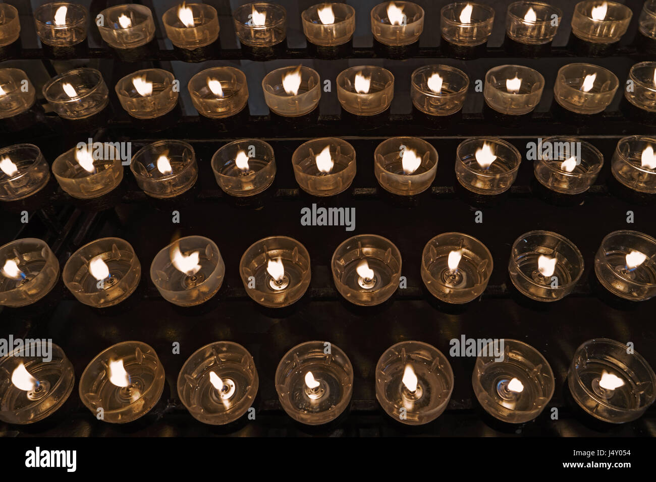 Beaucoup de brûler des bougies à l'église, un arrière-plan sombre. La lumière sacrée. La notion de religion. De nombreuses bougies allumées dans des chandeliers sur noir. Jaune lumineux Banque D'Images