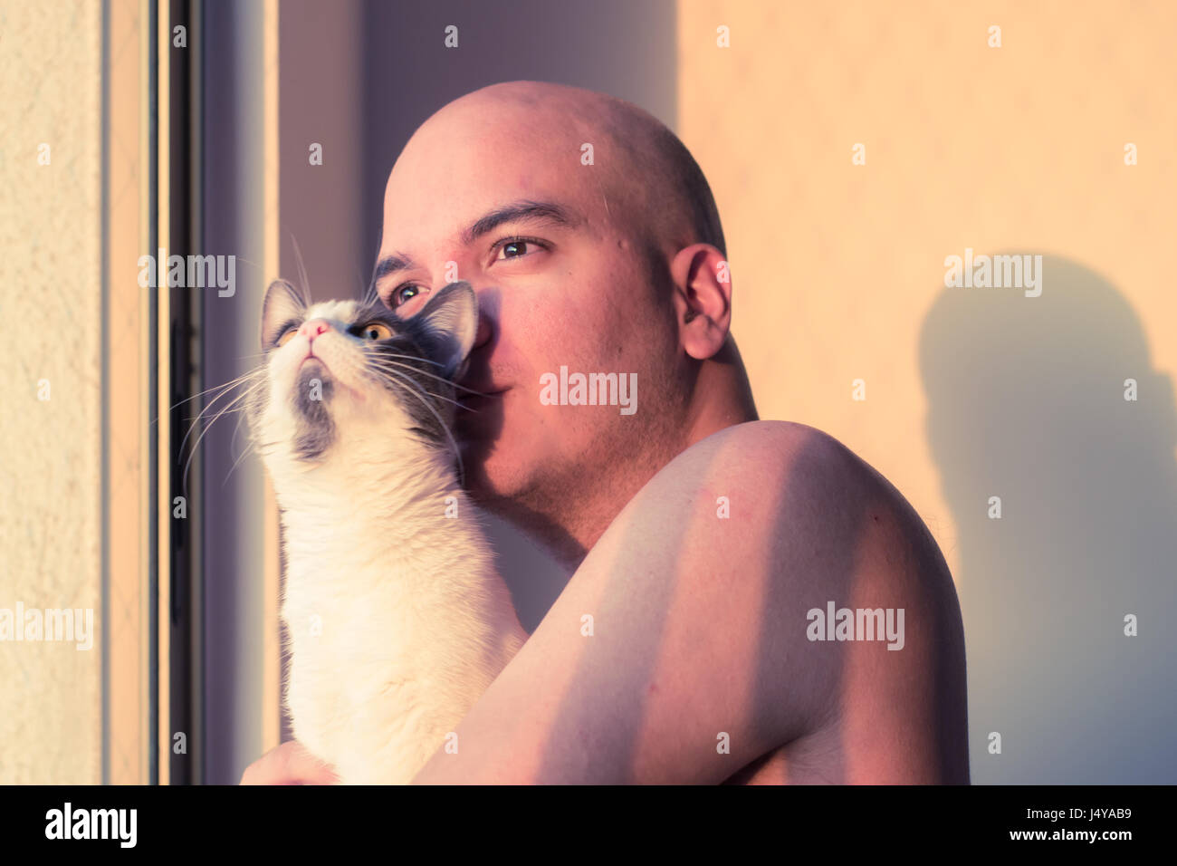 Pensive man holding a cat au coucher du soleil Banque D'Images