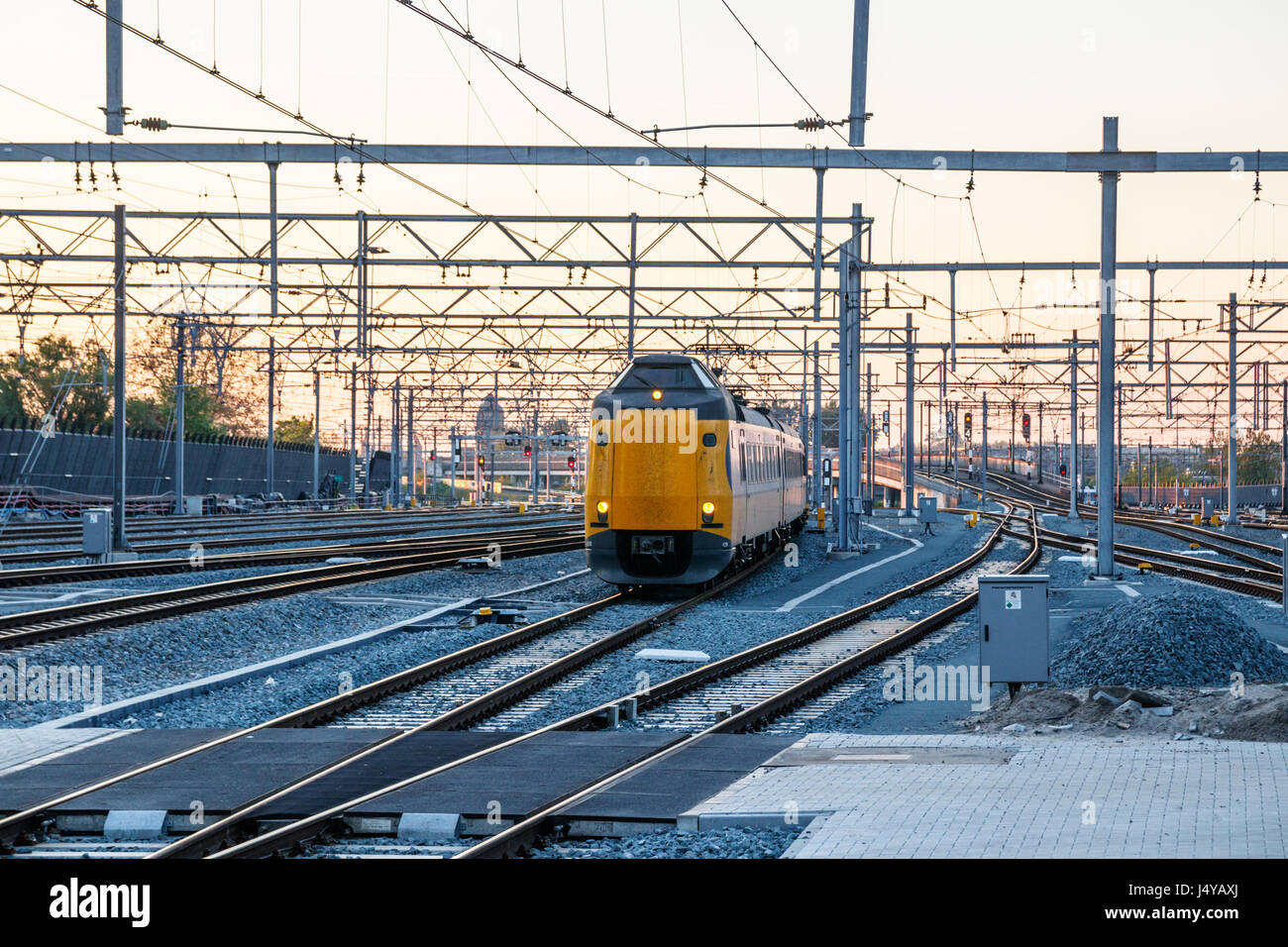 Northern Rail Yard d'Utrecht Centraal Station ferroviaire avec l'approche d'un train de passagers pendant le coucher du soleil. Utrecht, Pays-Bas. Banque D'Images