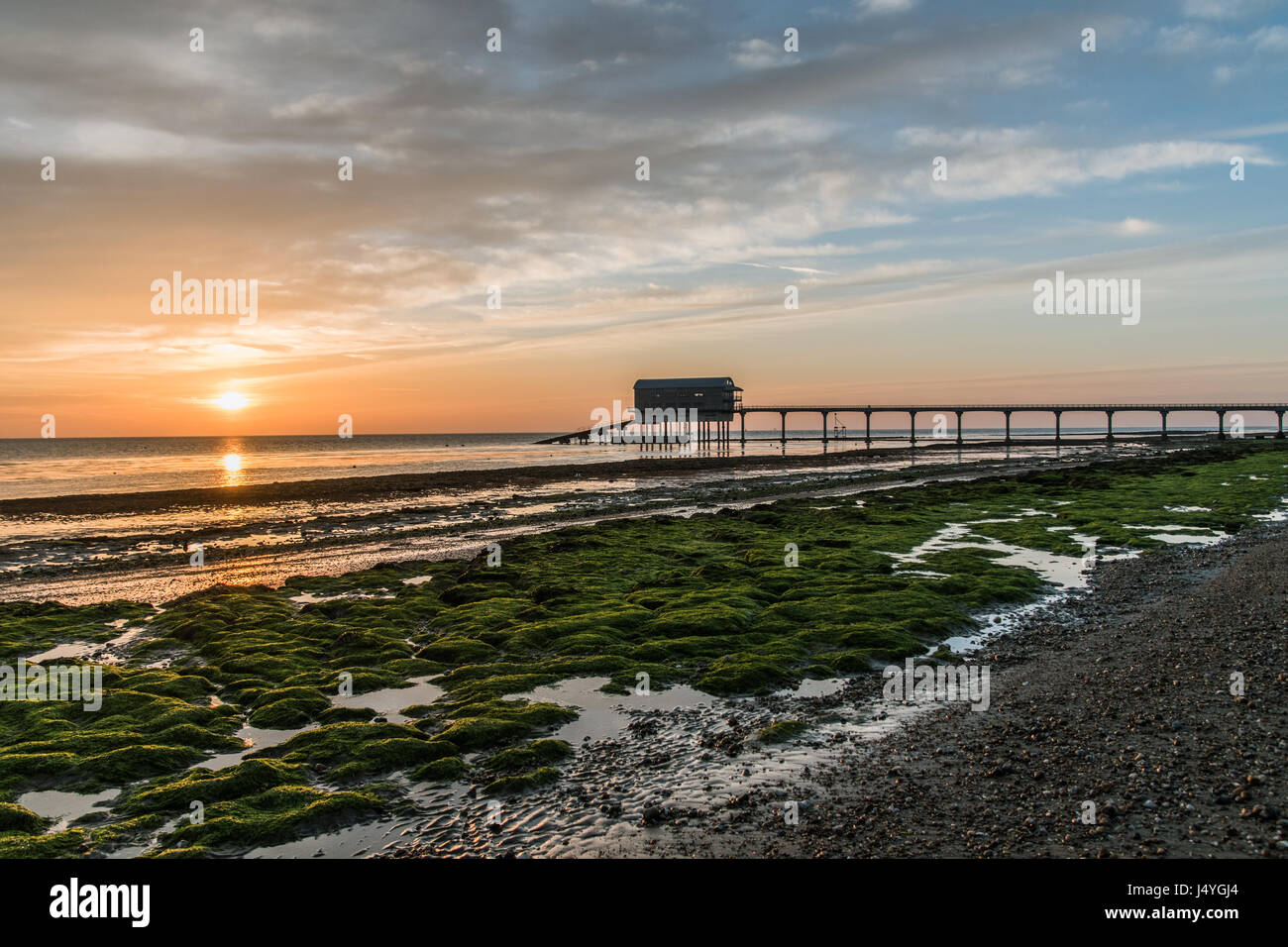 Lever du soleil à bembridge, île de Wight, de la jetée et de faire voile dans la distance, algues vertes lumineuses lueur rouge dans le soleil Banque D'Images