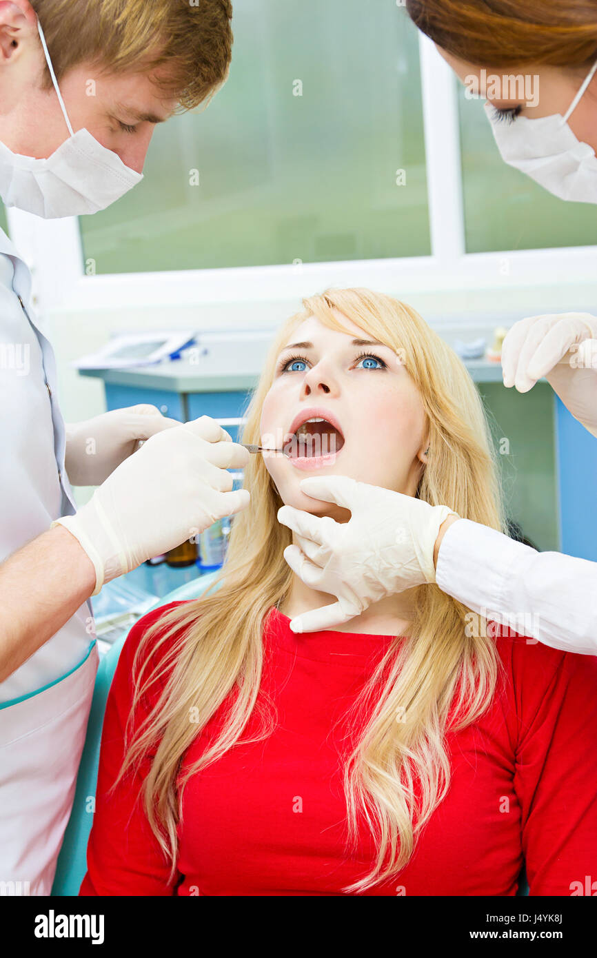 Closeup portrait jeune femme, femme, patient assis dans la chaise du dentiste, office, bouche ouverte, l'examen oral se fait par procédure médecin, assis Banque D'Images