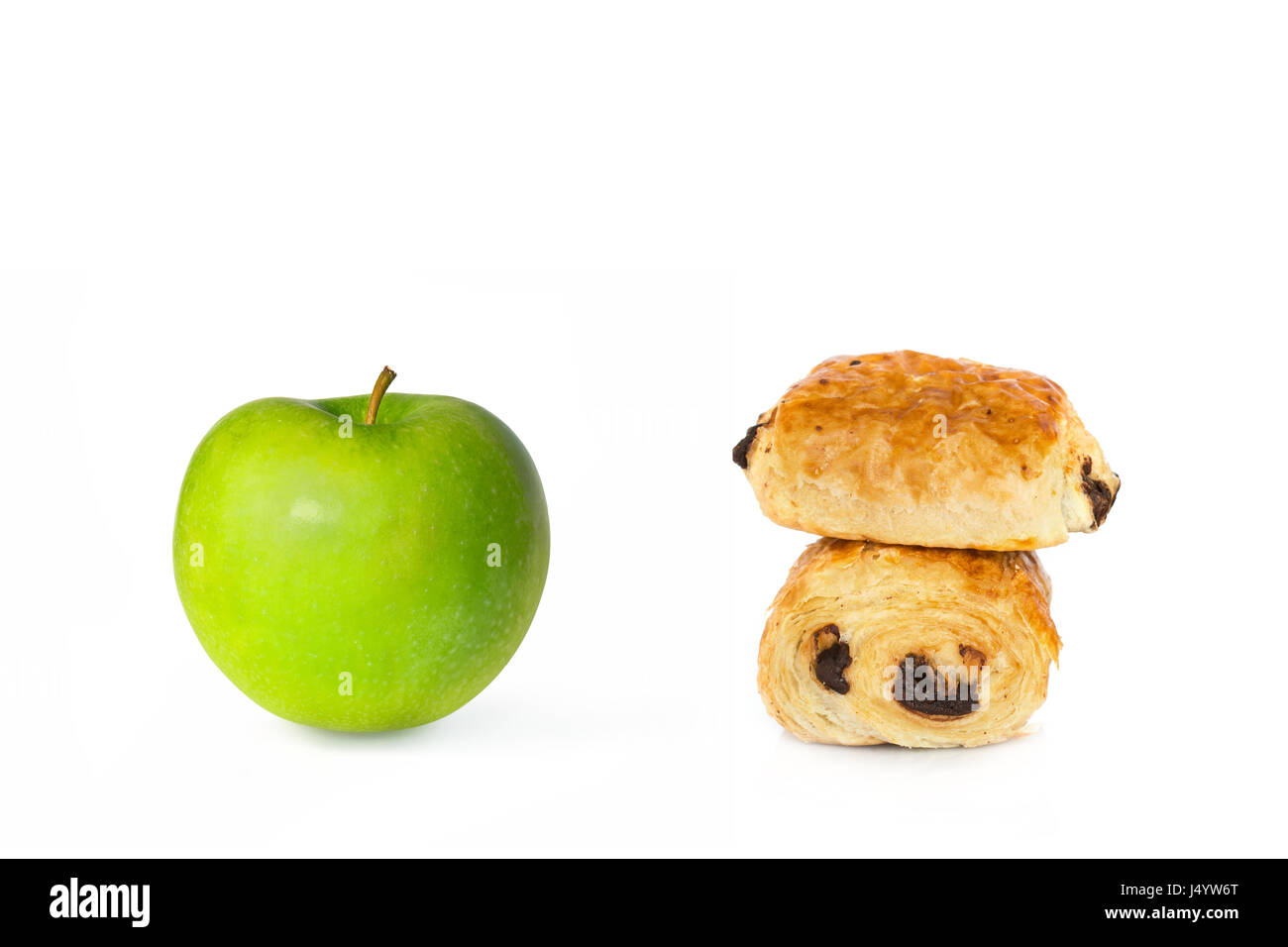 Pains au chocolat et une pomme verte sur fond blanc, les choix alimentaires sains ou malsains concept Banque D'Images