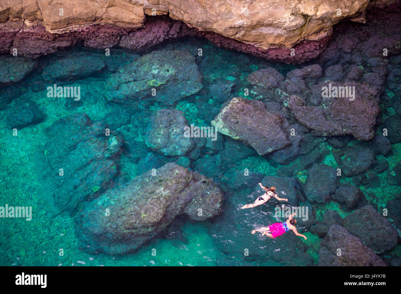 Vue depuis les falaises rocheuses de nageurs d'explorer les eaux limpides de la Méditerranée d'une anse de la côte de Dubrovnik, Croatie Banque D'Images