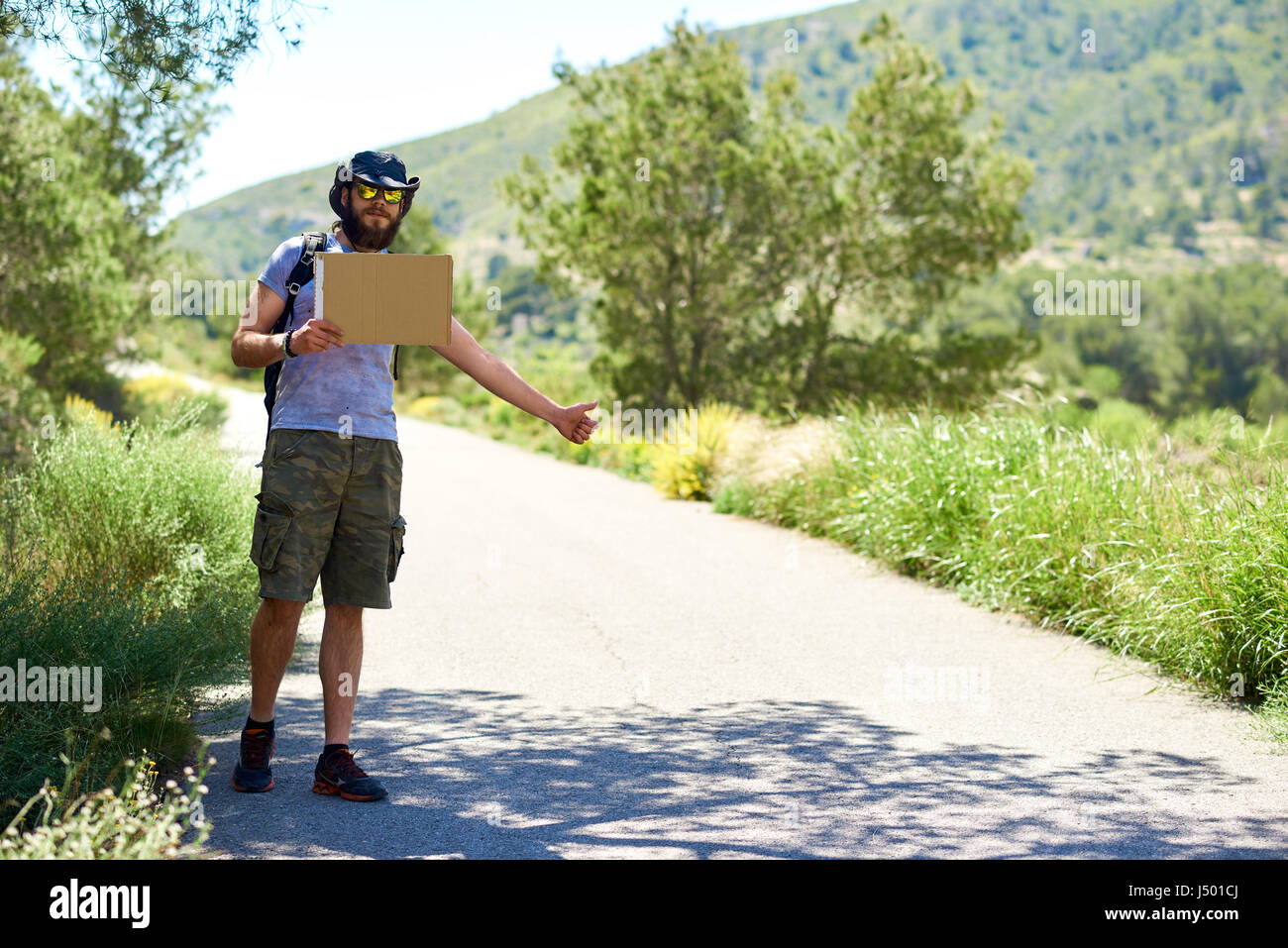 L'autostop voyageur avec un carton vierge signe sur une route de montagne. Le budget de voyage. Arrêt automatique Banque D'Images