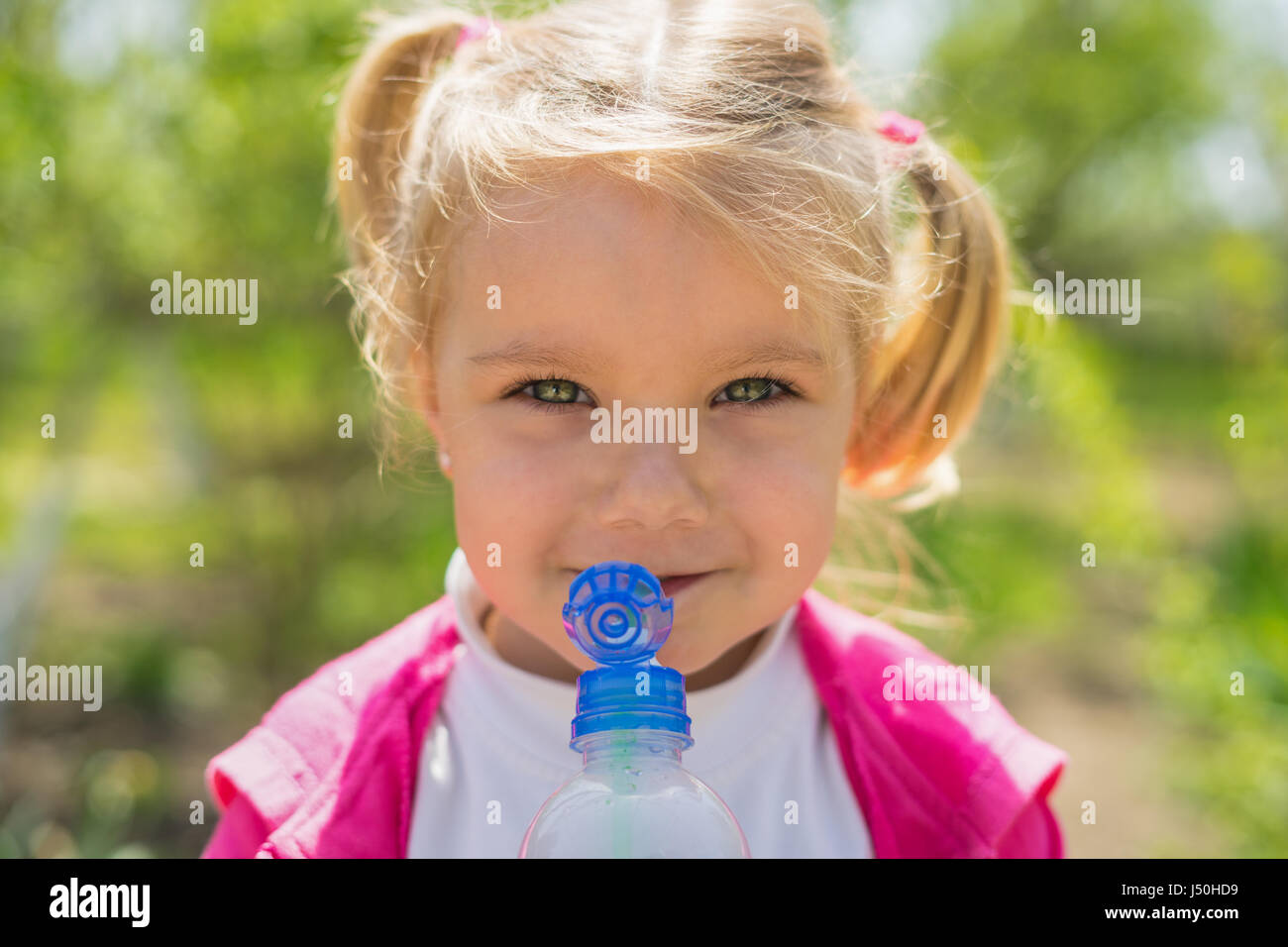 Petite fille mignonne l'eau potable de la bouteille en plastique. photo ensoleillée Banque D'Images