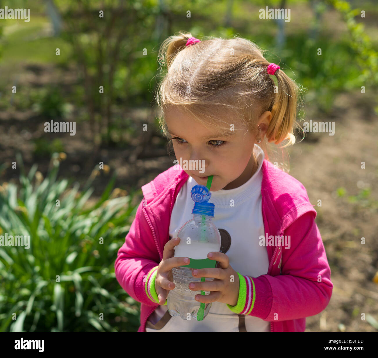 Petite fille mignonne l'eau potable de la bouteille en plastique. photo ensoleillée Banque D'Images