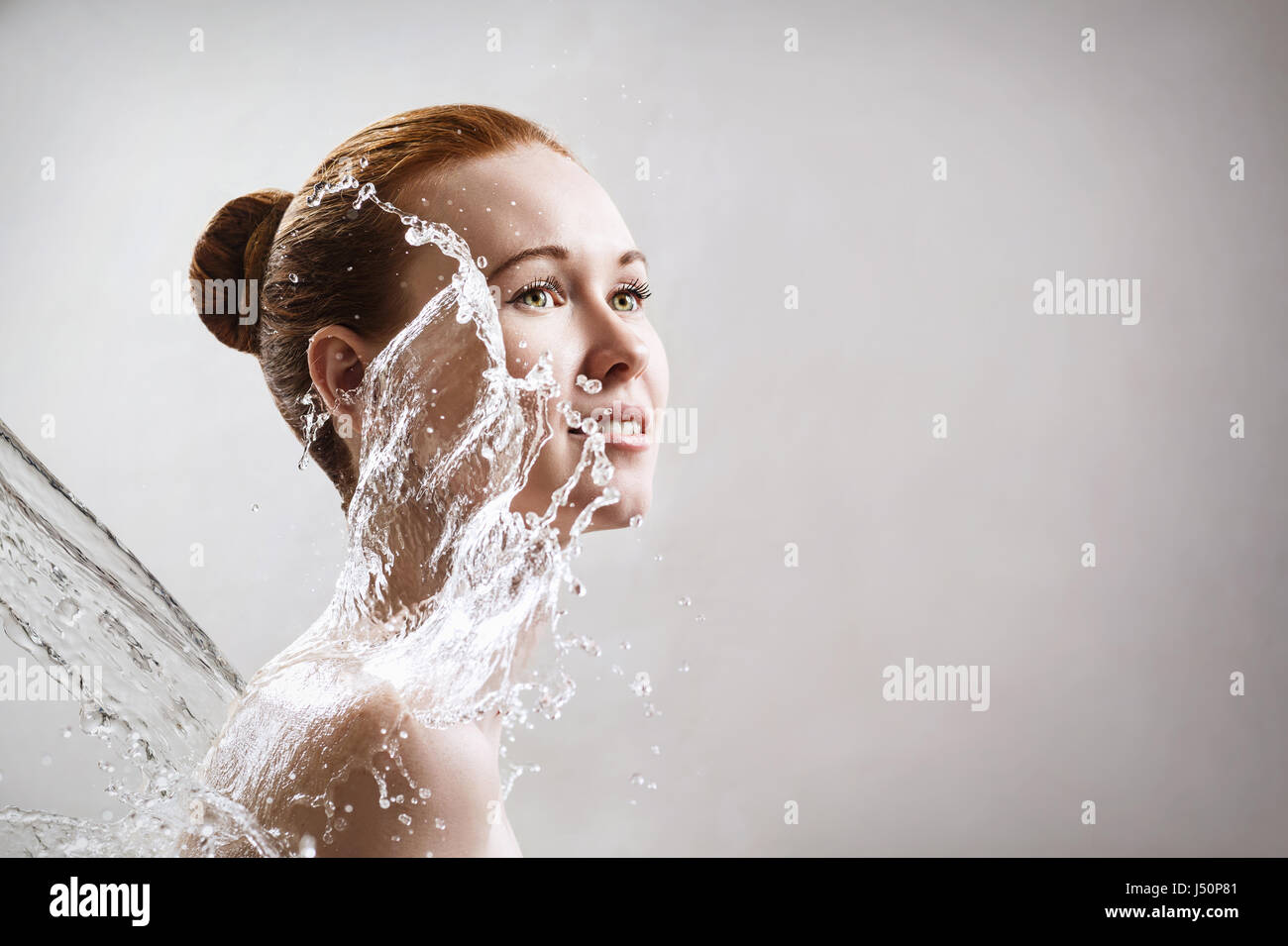 Belle jeune femme dans les éclaboussures de l'eau claire. Concept nettoyants et hydratants. Banque D'Images