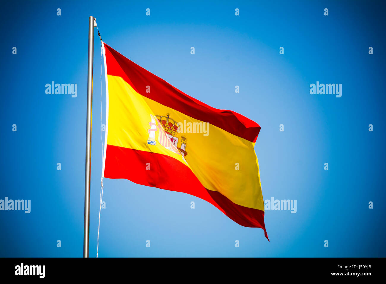 Espagne flag fluttering against blue sky sur sunny day Banque D'Images