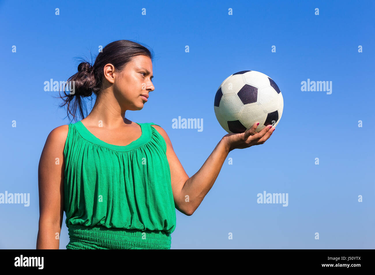 Young woman holding colombienne football sur la main avec ciel bleu Banque D'Images