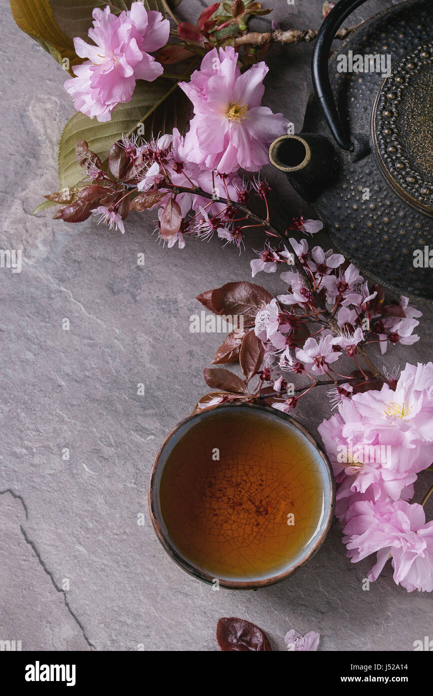 Fer noir, théière et tasse de thé traditionnel en céramique avec fleurs rose blossom cherry branch sur fond texture gris. Vue de dessus avec l'espace, Asiatique Banque D'Images
