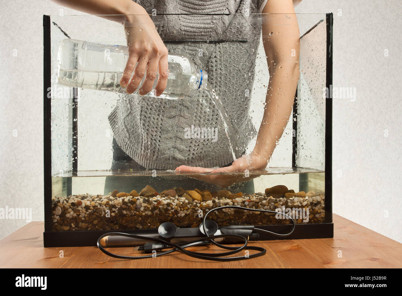 Mains d'aquariophile verser de l'eau dans l'aquarium d'une bouteille Banque D'Images