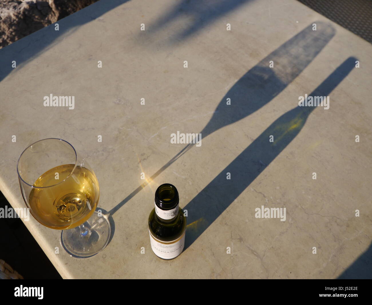 Verre de vin et la bouteille sur table avec de longues ombres Banque D'Images