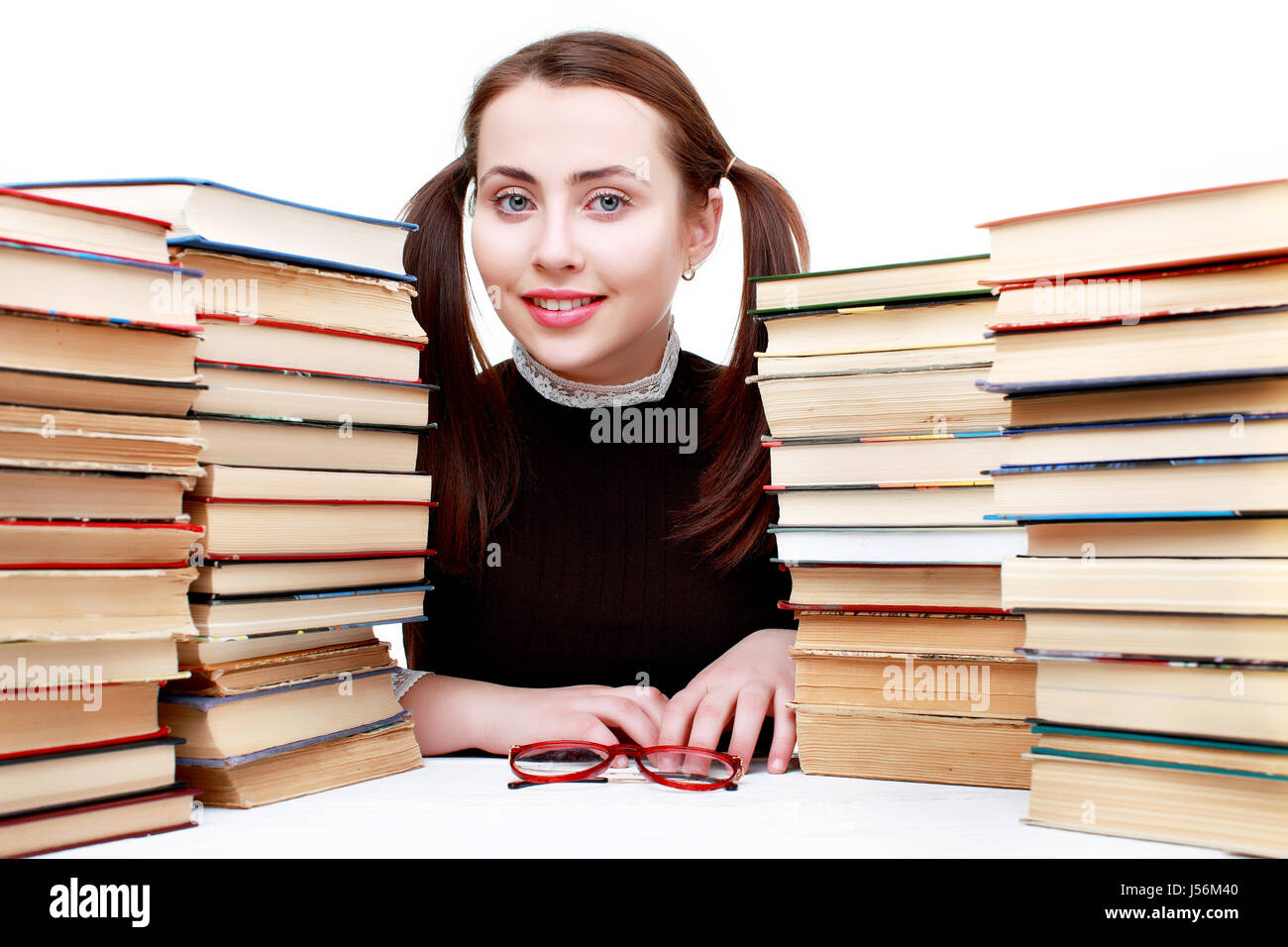 Jeune fille drôle assis au bureau avec des livres . Isolated on white Banque D'Images