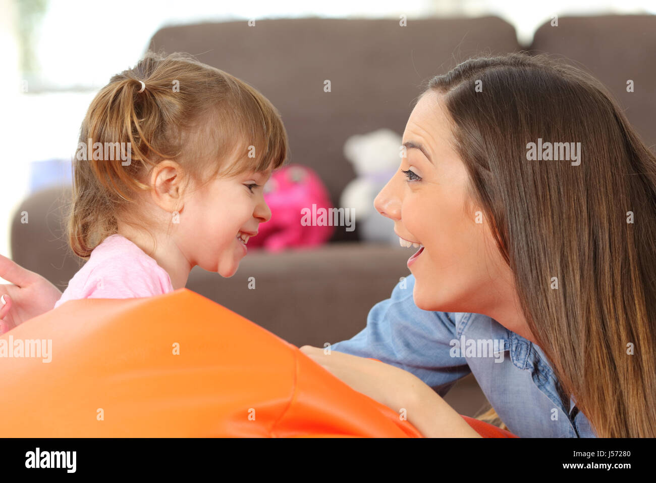 Vue latérale du portrait d'une mère heureuse et 2 ans fille de bébé face à et à faire des blagues dans la salle de séjour à la maison Banque D'Images