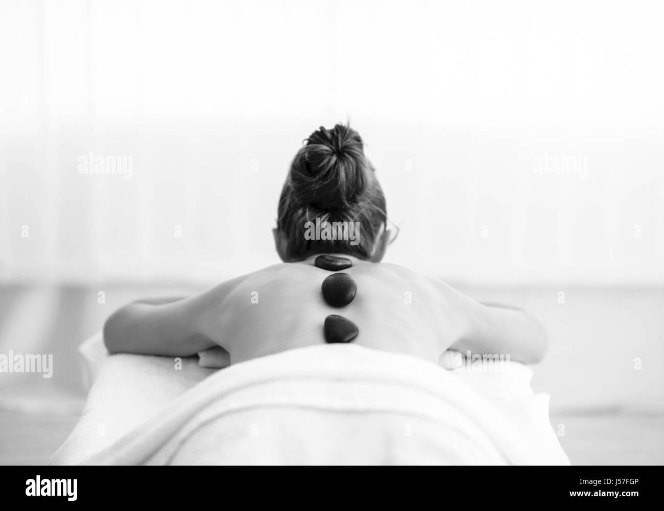 Young woman receiving massage aux pierres chaudes. Vue arrière Banque D'Images