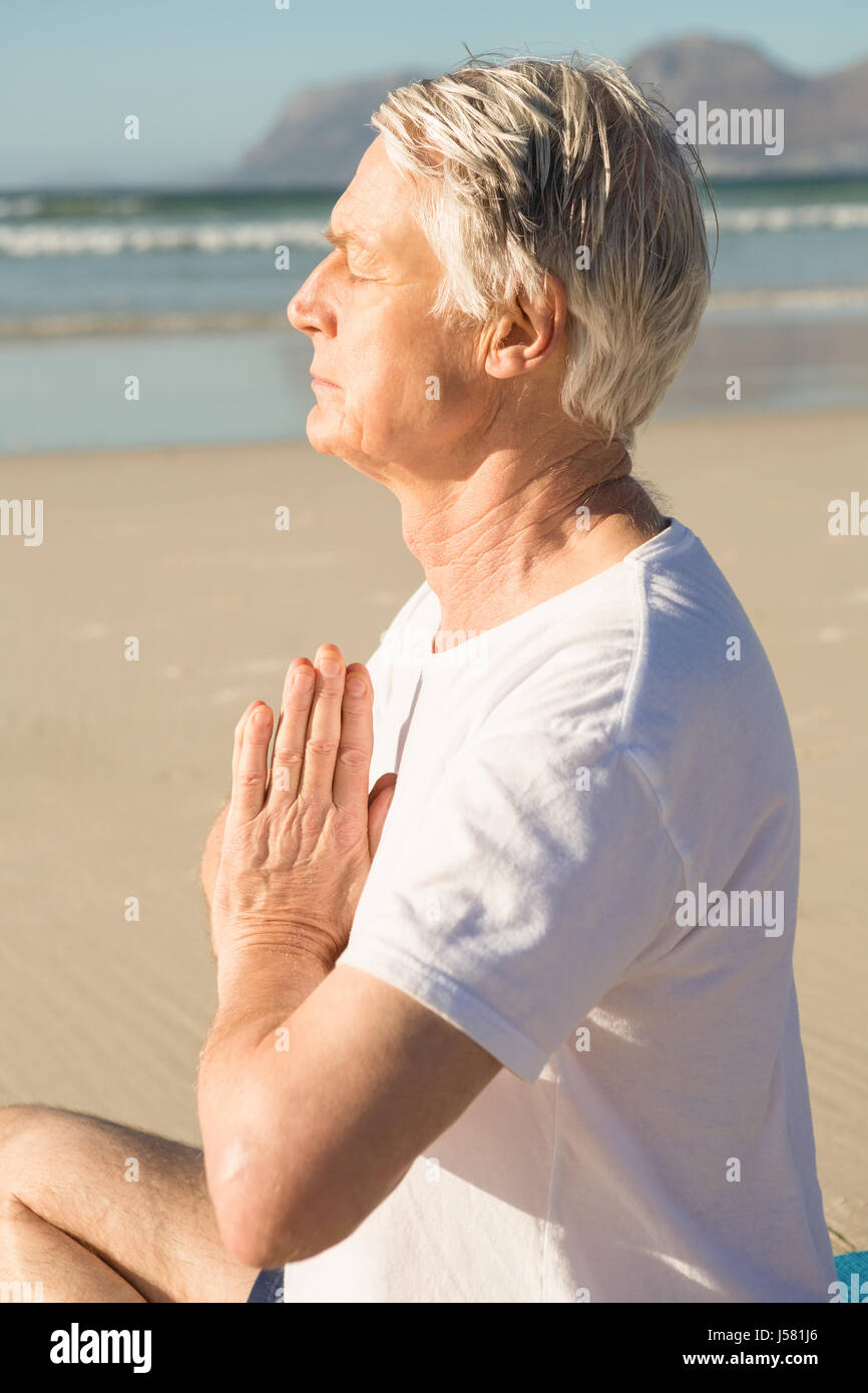 Ssenior yoga à plage en journée ensoleillée Banque D'Images