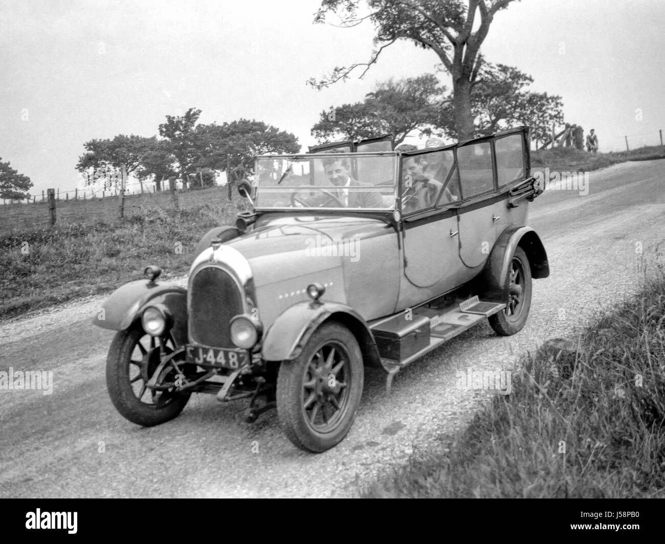 Un groupe de personnes pour un lecteur dans un Bean hp 11,9voiture décapotable à quatre portes construite en 1926 et enregistrée pour la première fois sur l'île de Bute. Deux hommes sont dans les sièges avant, le passager est titulaire d'un sac de golf, et une dame est sur le siège arrière. En haut de la photo d'un cycliste est à venir autour du coin. La photographie a été prise en 1931. Restauré à l'aide d'un scan haute résolution prises à partir du négatif original. Banque D'Images