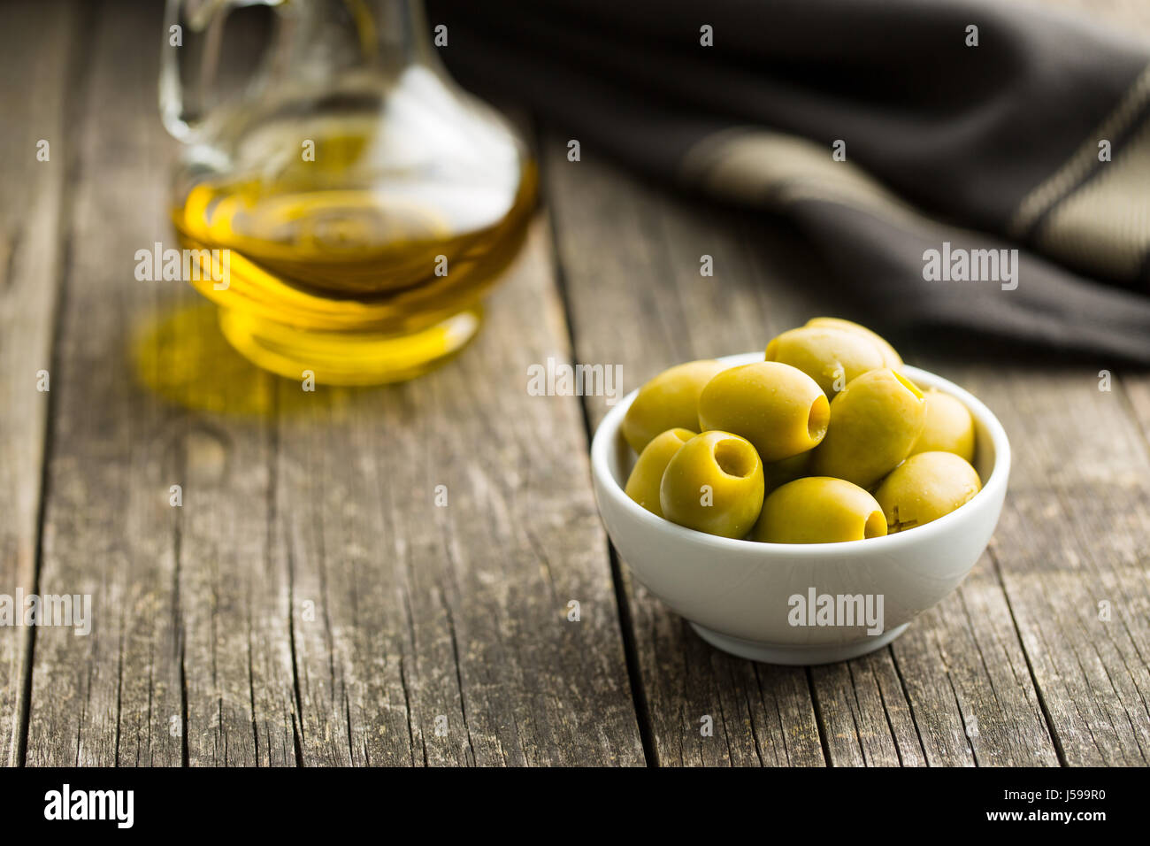 Les olives vertes dans un bol sur le vieux fond de bois. Banque D'Images