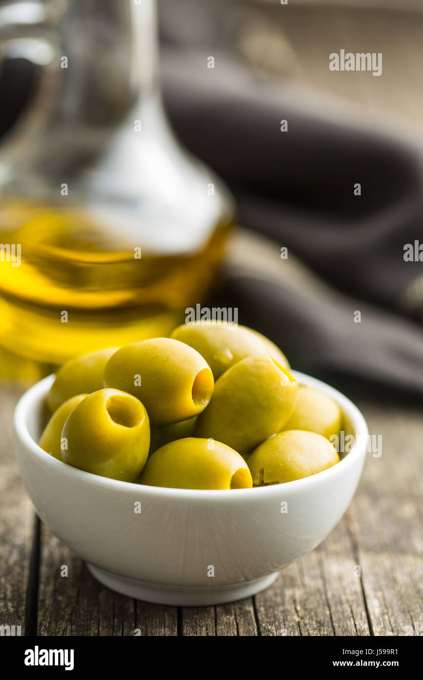 Les olives vertes dans un bol sur le vieux fond de bois. Banque D'Images