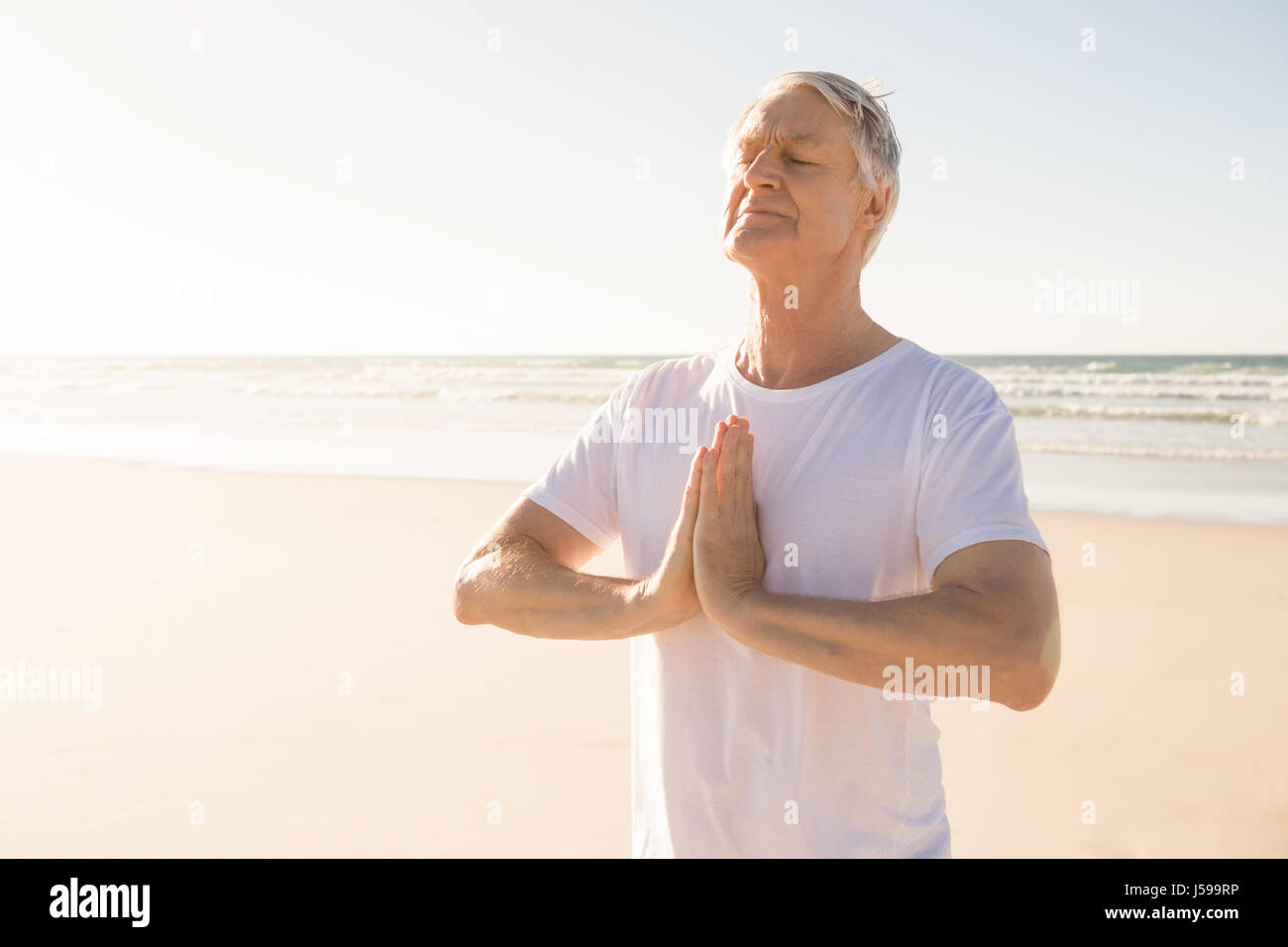Man avec les yeux fermé en position de prière at beach Banque D'Images