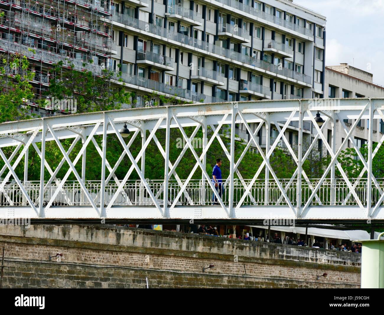 Man crossing passerelle au-dessus du bassin de l'Arsenal, avec blanc salon des antiquaires tentes et les foules vu dans l'arrière-plan. Paris, France. Banque D'Images
